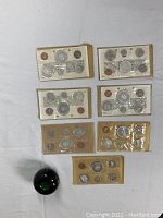 Overhead view of all seven sealed mint sets with green glass sphere for size reference