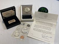 Overview of lot with Franklin Mint medallion, Papal Visit coin set, Singapore Airlines silver ingot bar, certificate and reference object.