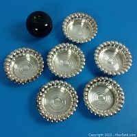 Six silver plate coasters arranged together showing the overall design and size relative to a 3 inch green apple for scale.