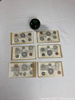 Six sealed mint sets displayed with size reference apple