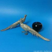 Two silver plated pheasant figurines displayed side by side with a black apple object for size reference on blue background.