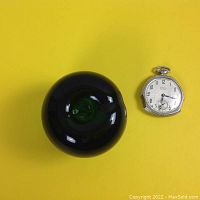 Watch next to green glass apple for scale