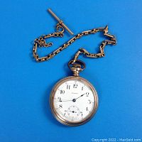 Front view of pocket watch and attached chain on blue background