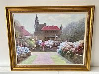 Front view of the framed oil painting showing the castle or manor house with red roofs and colorful garden foreground.