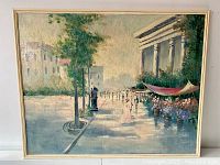 Full view of the framed oil painting depicting a street scene with buildings, trees, people, and a columned structure with a flower stand.