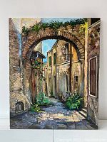 Front view of painting showing a street scene with archway and buildings under blue sky.