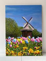 Front view of entire oil painting depicting windmill above tulip field