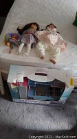 Photo of two dolls, small Troll figurine, and boxed Journey Girls kitchen play set on mattress