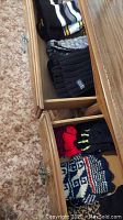 Drawer of various knit hats and scarves in different colors and styles, showing overall lot contents.