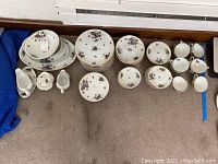 Overview of entire dinnerware set showing plates, teacups, bowls, and serving pieces arranged on floor