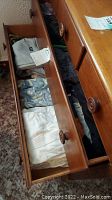 Dresser drawer open showing folded white, patterned, and solid men's shirts and shorts