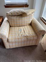 Rowe chair and a half with a yellow, grey, and white plaid fabric pattern. One plaid throw pillow seen on seat with beige throw pillow stacked behind.