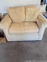 Front view of oversized chair with yellow and white small check pattern upholstery. Features two pillows and armrest covers, sitting on carpet.