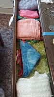 Drawer with assorted scarves in multiple colors including light colors such as pink, peach, white, blue tie-dye, and multicolored items.