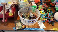 Long shot showing assortment of items on a table including wooden wagon, barrel bank, plastic container with figures, and numerous TMNT figures.