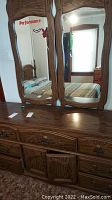 Full frontal view of wooden dresser with three-panel mirror showing overall condition and size relative to room.