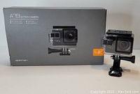 Apeman A79 action camera in waterproof housing displayed next to its original box showing the camera features and branding.