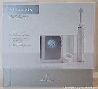 Photo of the boxed set of Elements sonic toothbrush with UV sanitizing base by dazzlepro, showing product image, branding, and key features on the box