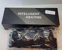 Photo showing the Intelligent Heating box and the black heated gloves in plastic packaging with control button visible