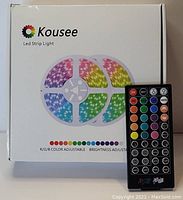 Box of Kousee LED strip light set showing two rolled LED strips in RGB colors and the remote control.