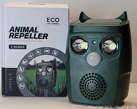 Photo of the ultrasonic animal repeller device next to its box showing product details and branding.