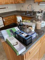 Photo of all the items arranged on a kitchen island showing multiple kitchen appliances and gadgets including Food Saver, vegetable chopper, and slicer.