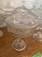 Close-up of one compote bowl with floral etched lid, smooth round pedestal base, clear glass