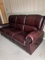 Front view of burgundy leather three-seater couch showing overall condition and design