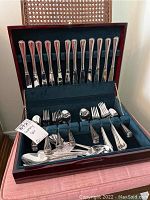 Overall shot of the cutlery set inside a wooden case showing complete set of knives, forks, spoons, and serving utensils.