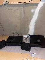 Overview of the stereo equipment set including receiver, Yamaha CD player, Bose speakers, and remote controls on a white surface against a concrete wall.