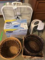 Lot items including Lasko white plastic box fan, Sunbeam humidifier, Dr. Scholl's foot spa boxed, and two wicker baskets.