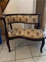 Front view of the solid wood settee showing floral upholstered seat and backrest with dark wooden frame and curved legs.