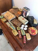 Overhead view of collection of assorted vintage tins and boxes on wooden surface, showing variety of product types and brands.