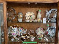 Overall view of two hutch shelves containing porcelain and glass items.