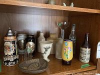 Shelf containing various vintage vases, bottles, chokin, stein and small dish.