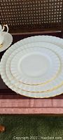 Stack of three plates showing scalloped edge and gold trim