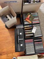 Wide view showing multiple open boxes and cases full of CDs arranged in rows on the floor, showing the quantity and storage method.