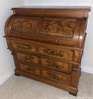 Front view of roll-top desk closed showing two burled veneer tambour panels and brass drawer fronts