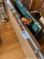 Two hard cases, one tan and one dark green, with a pair of noise reduction earmuffs resting on the tan case.