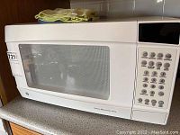 Front view of white GE sensor microwave oven showing door and keypad