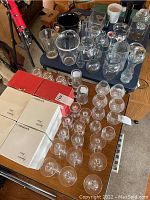 Top view of a table covered with a variety of glassware including boxed stemware and loose glasses of different types and sizes.
