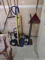 Two hand trucks side by side, showing size and color difference. Yellow heavy duty with blue handle, black lighter duty hand truck.
