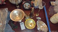 Photo showing multiple small sterling silver items including goblets, pedestal dish, trumpet-shaped piece, candlestick and glass with thin stem on a wooden table.