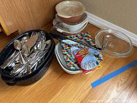Full lot overview showing black speckled roasting pan, stainless steel flatware, glass baking dishes with lids, and additional kitchen items.