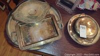 Overview of four silverplate serving pieces including trays, a smaller rectangular tray, and a covered dish with lid.