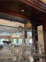 Front view of shelf showing clear and frosted crystal items including silver-plated bowl pedestals, shallow Lalique dishes, figurine and vases