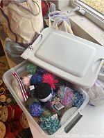 Storage container filled with multiple skeins of yarn in various colors and textures.
