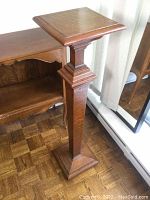Wooden pedestal plant stand, close-up showing square top with slight marks and decorative molding
