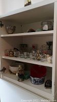 Overall shelving unit with assorted decorative items including candle holders, porcelain bowl, mosaic pitcher, and small décor pieces.