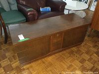 Closed wooden cedar storage chest with smooth finish and carved front expanding the length and holding the lid down. The chest is rectangular shaped with a flat top.